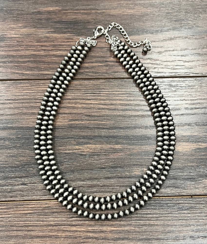 Multi strand silver beaded necklace on a wooden surface