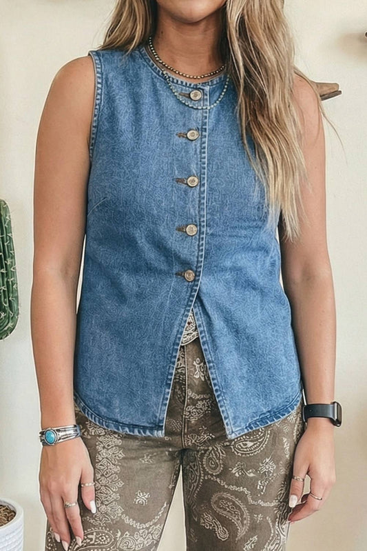 Person wearing a sleeveless denim button-up shirt with paisley pants against a neutral background