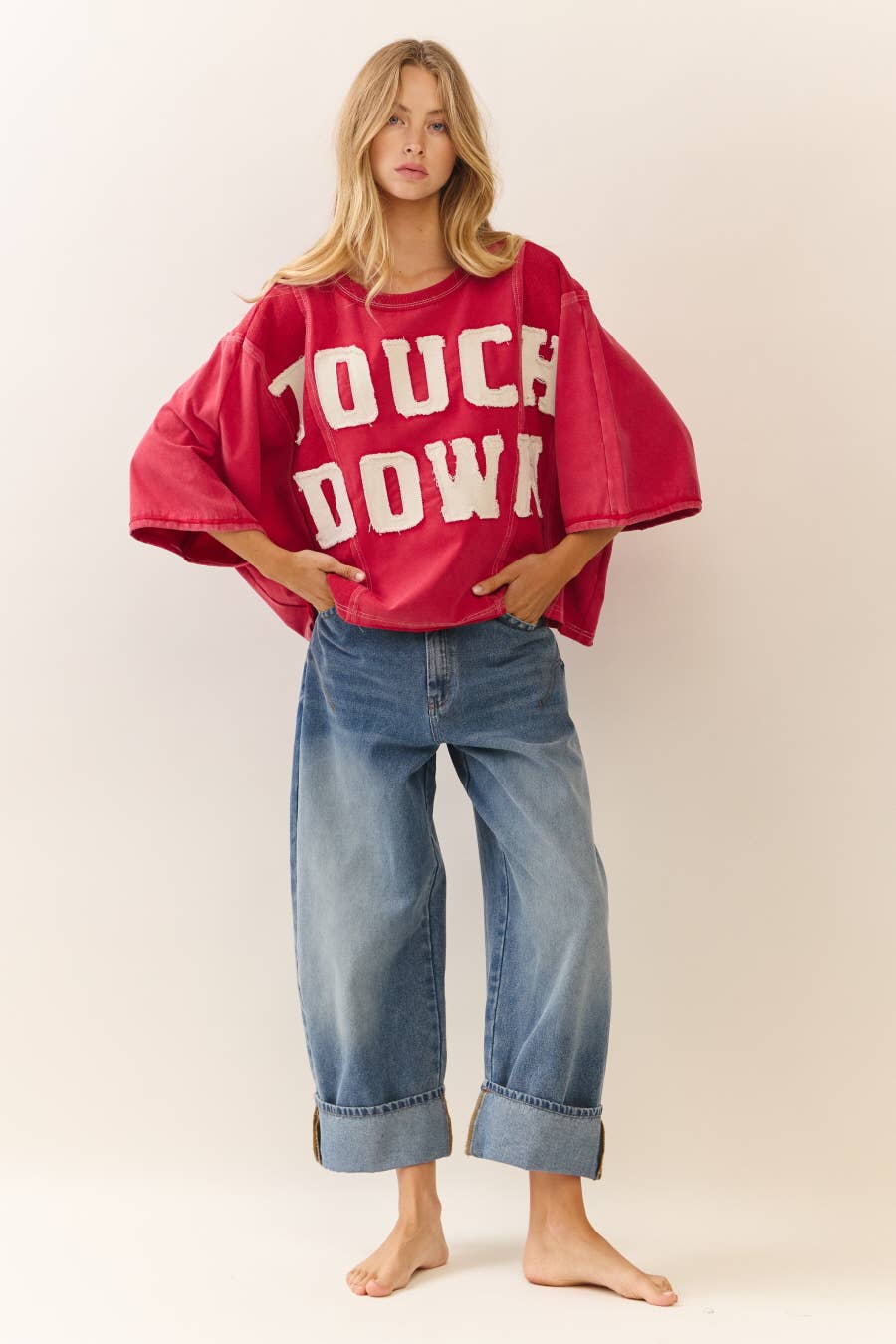 Person wearing a red 'TOUCHDOWN' shirt and blue jeans on a plain background