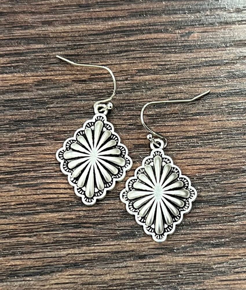 Silver floral earrings on a wooden surface