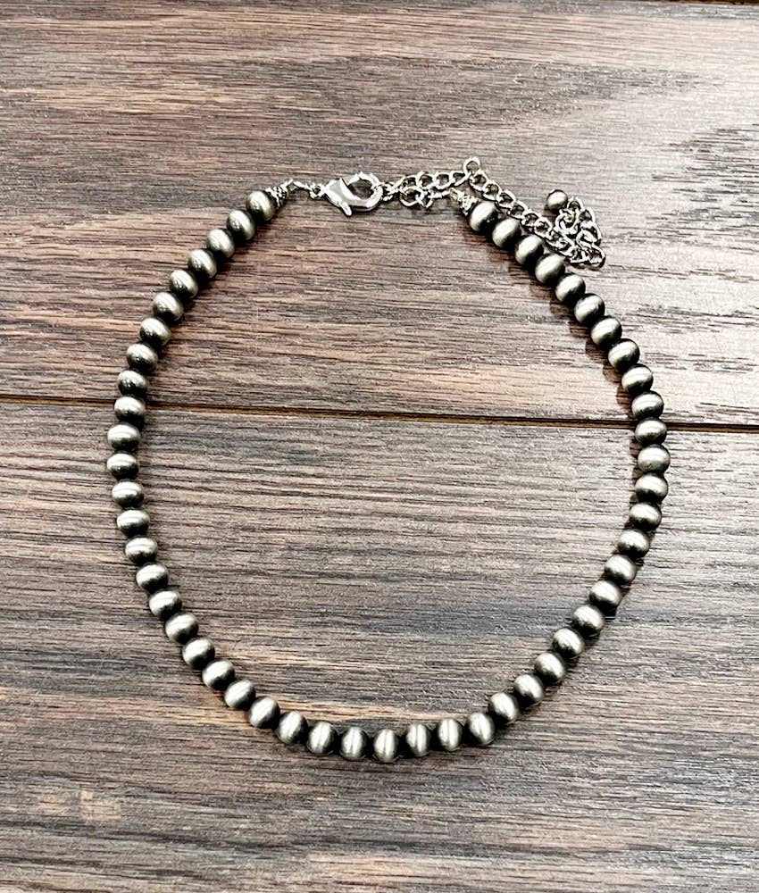 Silver beaded necklace on a wooden surface
