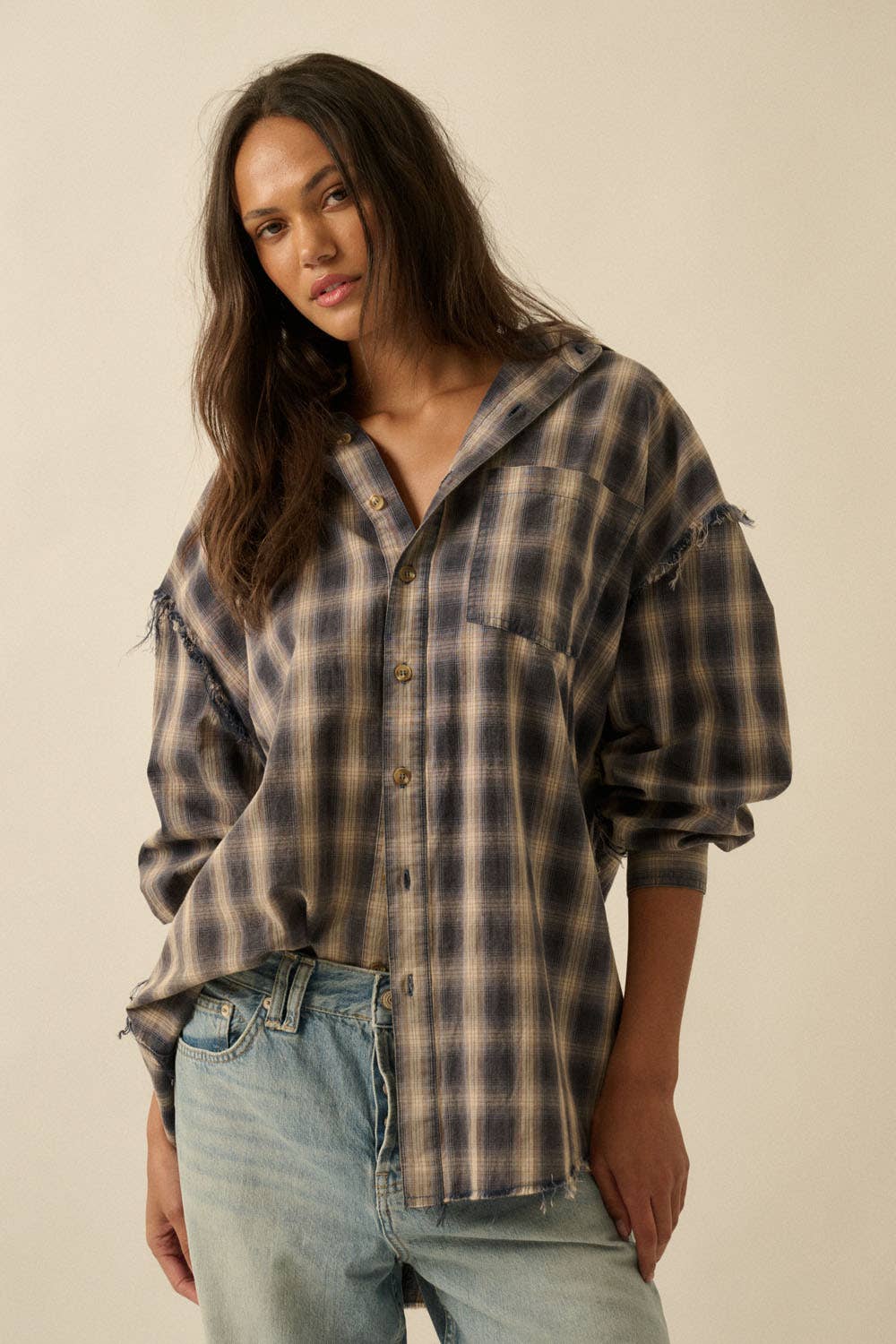 Woman wearing a plaid shirt and jeans against a plain background