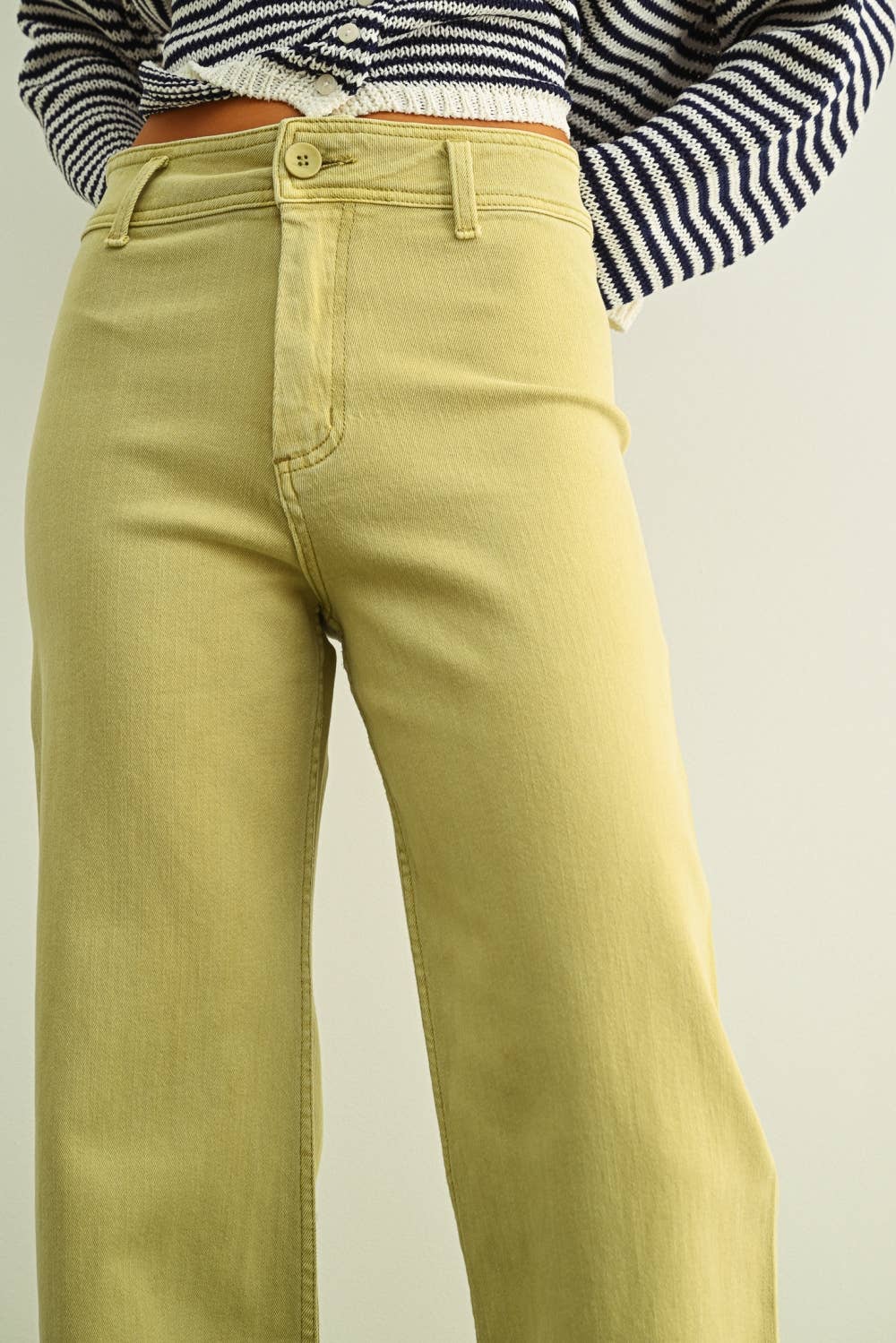 Light green pants worn with a striped shirt on a plain background