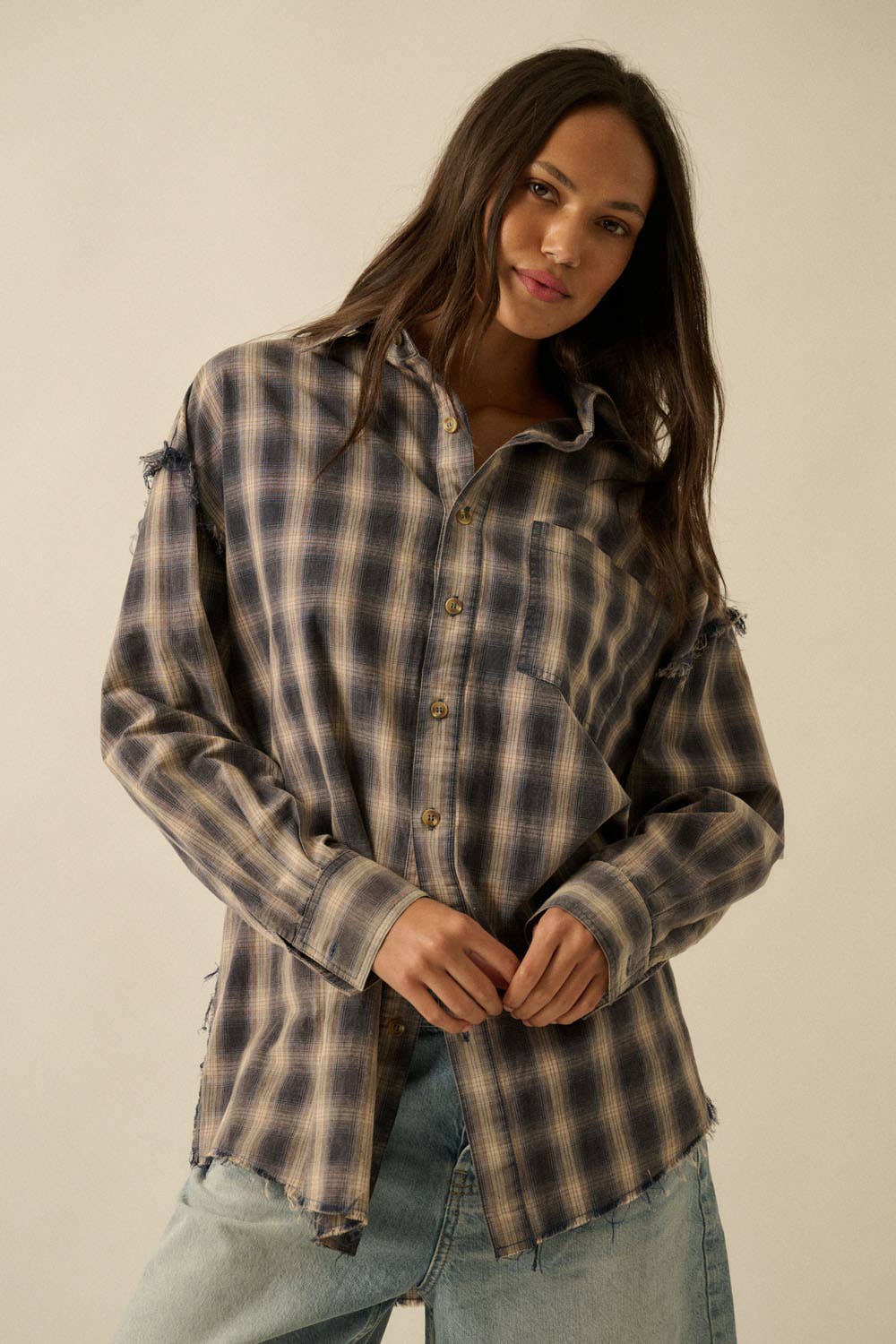 Woman wearing a plaid shirt and jeans against a plain background
