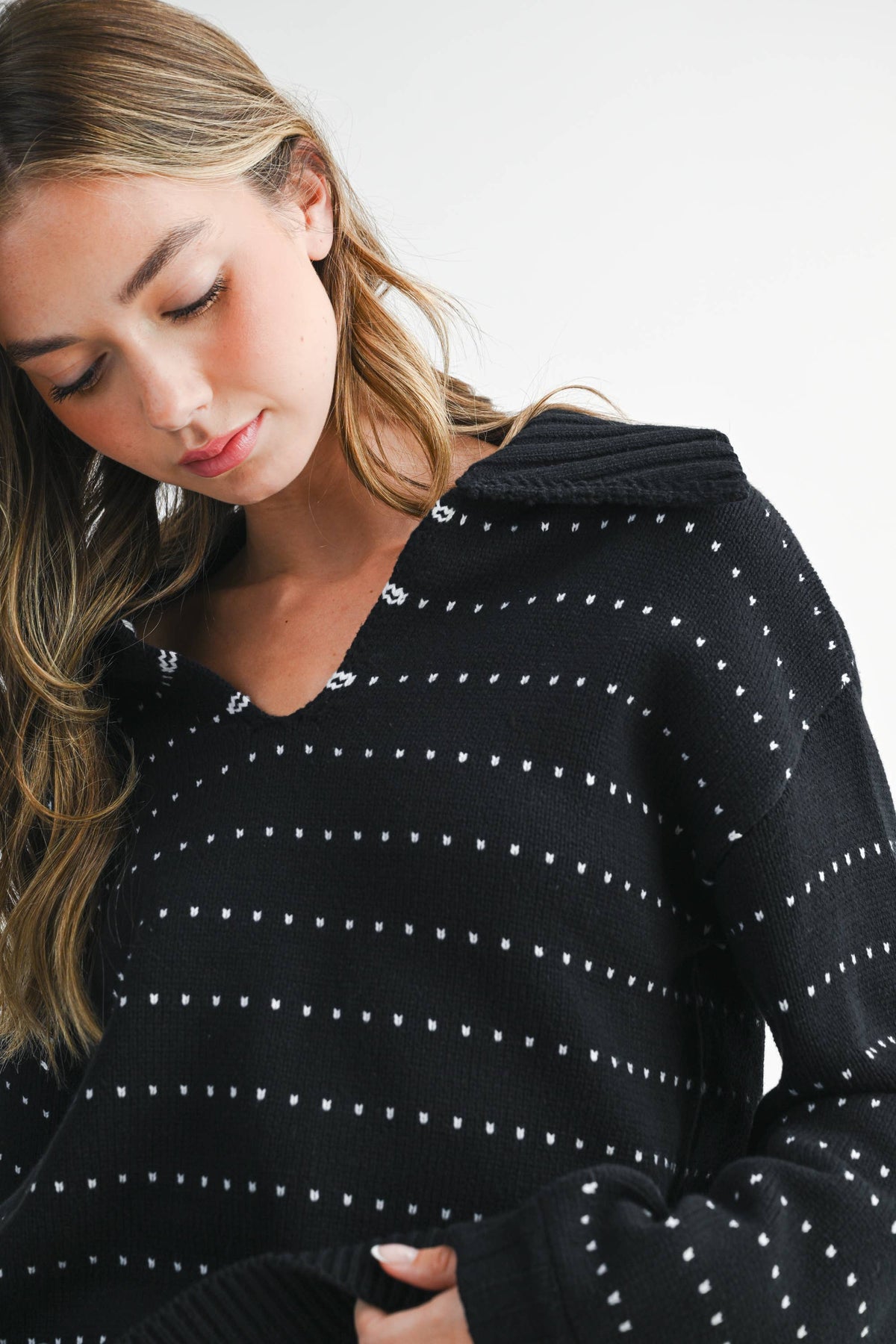 Woman wearing a black hoodie with white patterns on a plain background