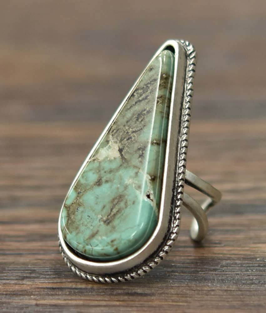 Turquoise stone ring with silver band on a wooden surface