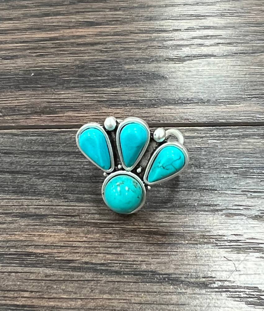 Silver ring with turquoise stones on a wooden surface