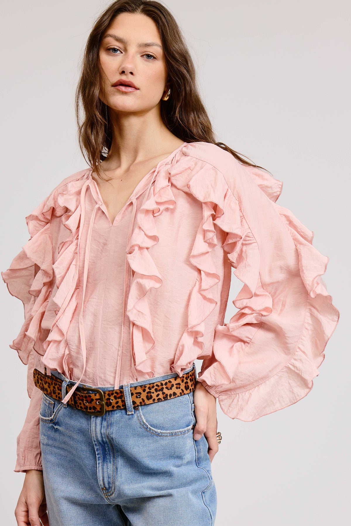 The Rosalie Ruffle Top blush pink tie-front ruffle blouse with long sleeves styled with jeans and leopard belt