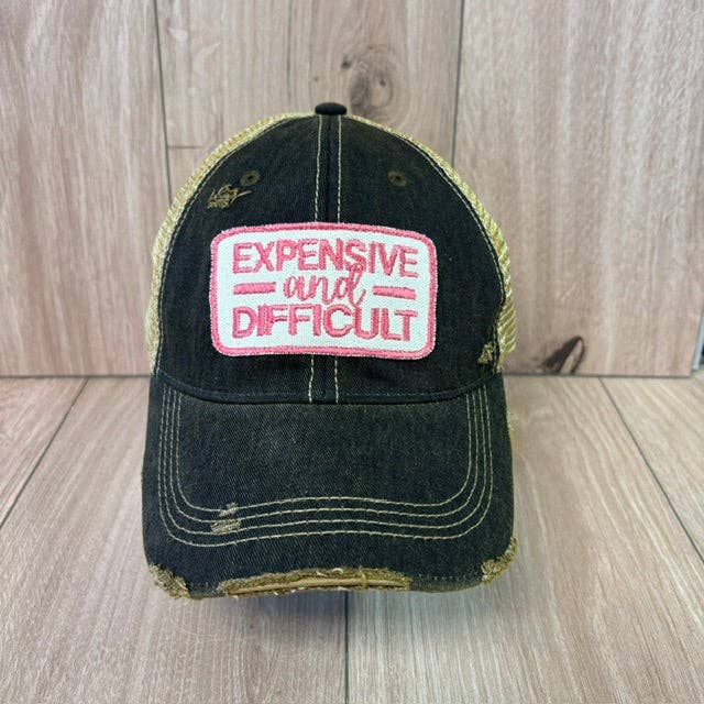 Black cap with pink and white text on a wooden surface
