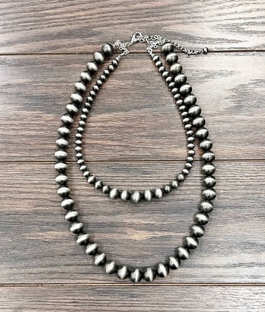 Silver beaded necklace on a wooden surface