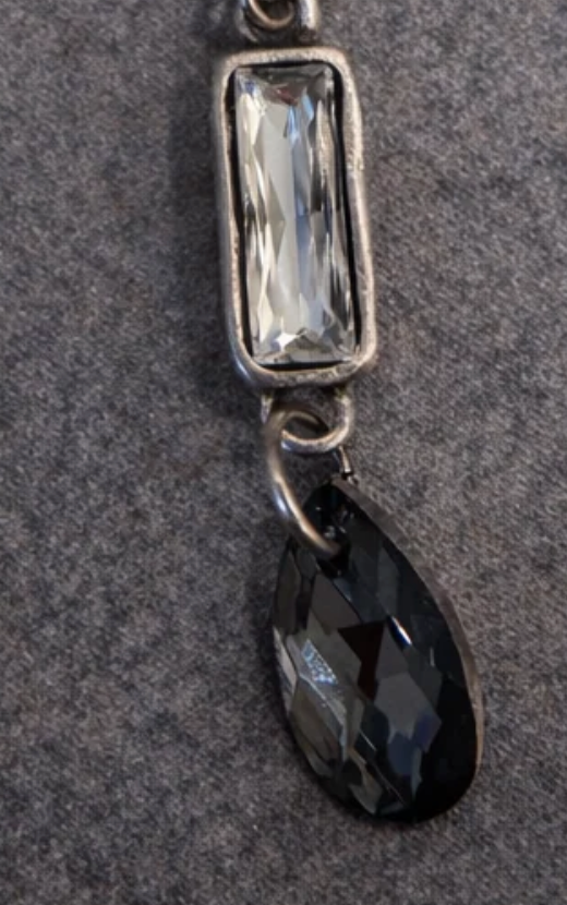 The Case Necklace pendant close-up with a clear baguette Austrian crystal and faceted black teardrop