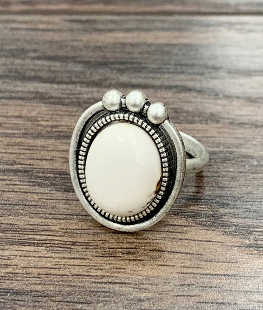 Silver ring with a white stone on a wooden surface
