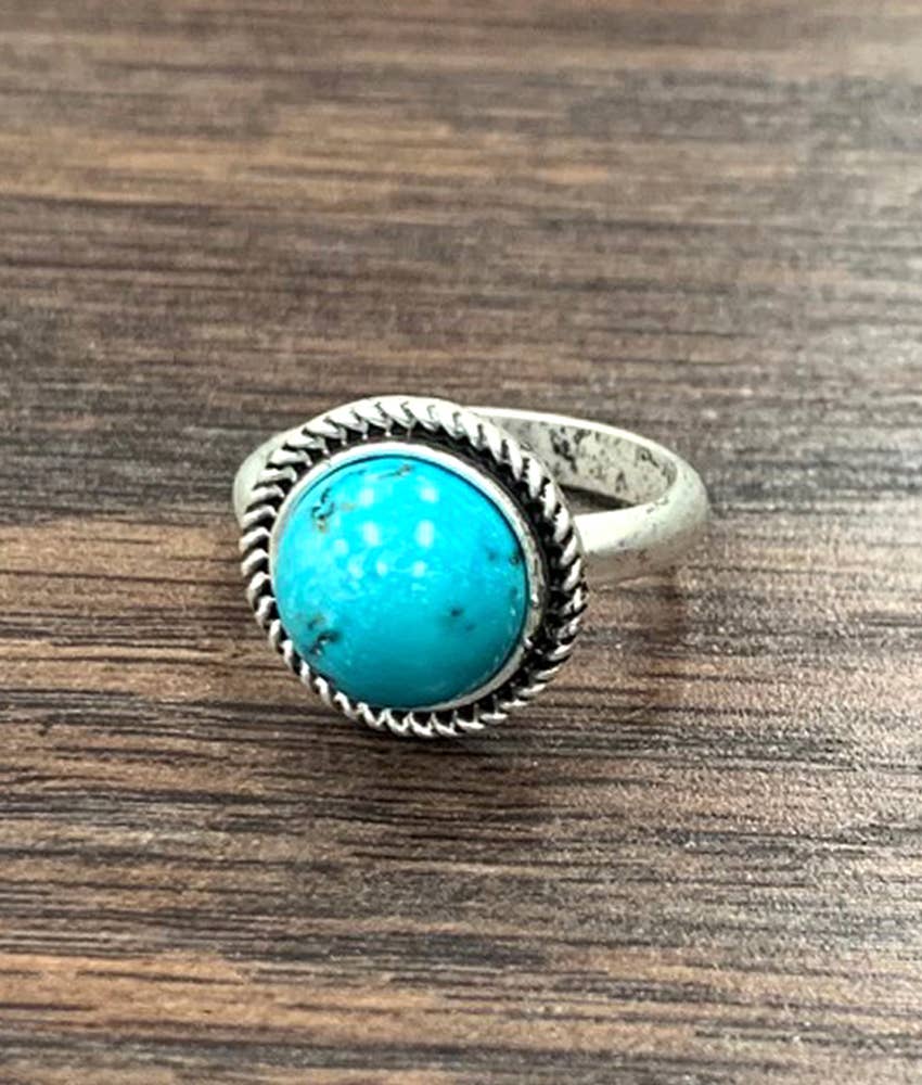 Silver ring with a turquoise stone on a wooden surface