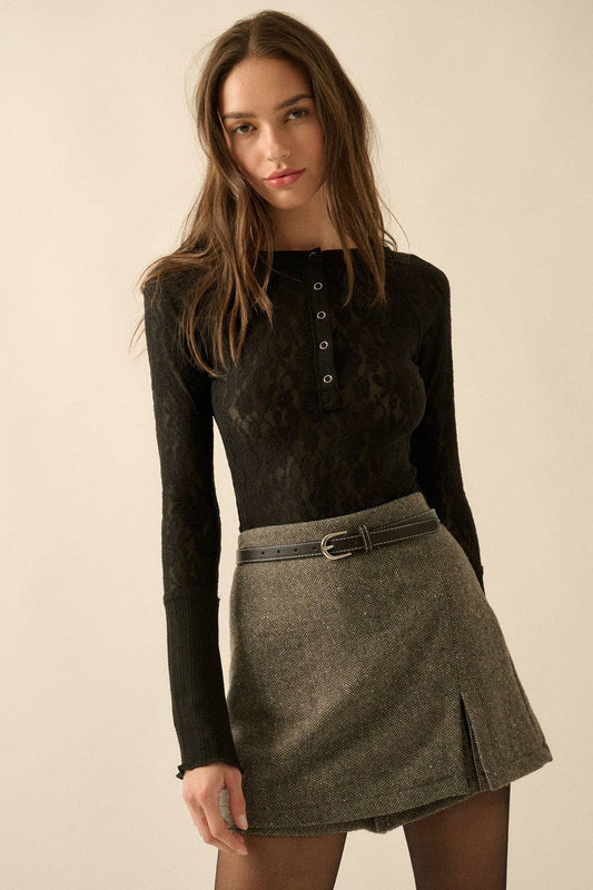 Woman wearing a black long-sleeve lace top and gray skirt on a beige background